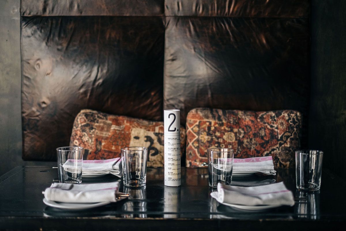 Leather banquette booth with kilim cushions and table number
